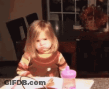 Little Girl Sitting At Table With Water Bottle GIF