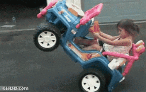 Little Girl Sitting In Blue Toy Car With Pink Steering Wheel GIF