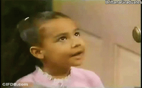 Little Girl Sitting In Front Of Door Looking At Camera GIF