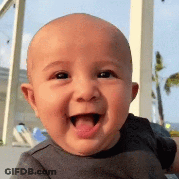 Little Girl Sitting In Front Of Door Looking At Camera GIF