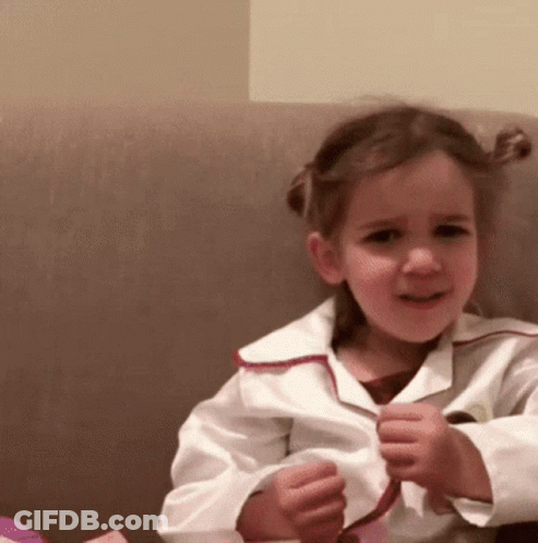 Little Girl Sitting On Couch Hands In Pockets GIF