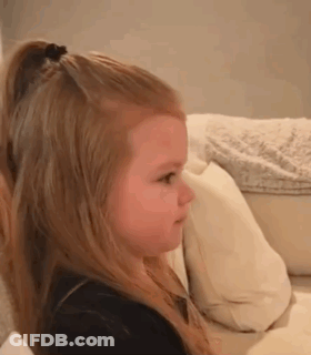 Little Girl Sitting On Couch Making Face GIF