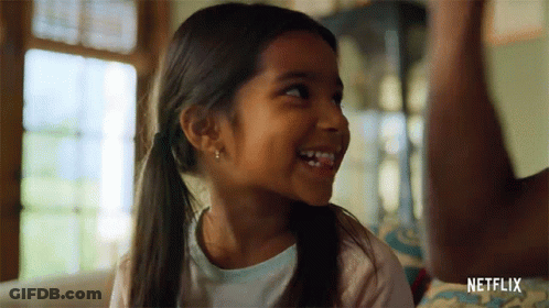 Little Girl Smiling On Couch In Front Of Netflix Logo GIF
