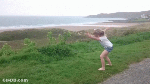 Little Girl Standing In Grass Near Ocean GIF