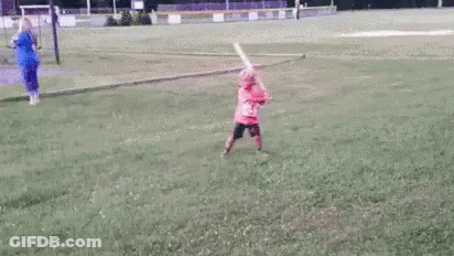 Little Girl Swinging Bat At Ball On Field GIF