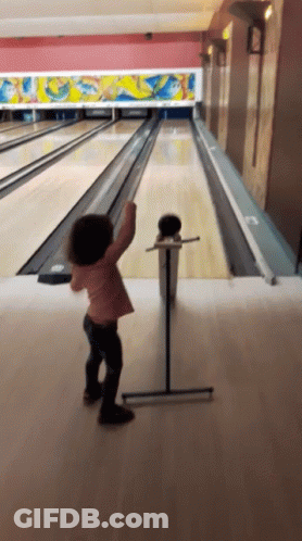 Little Girl Throwing Bowling Ball In Bowling Alley GIF
