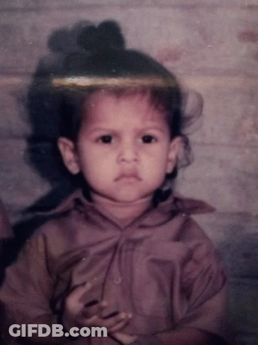 Little Girl With Bun On Head Looking At Camera GIF