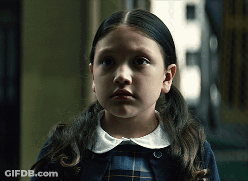Little Girl With Pigtails And Plaid Shirt Looking At Camera GIF