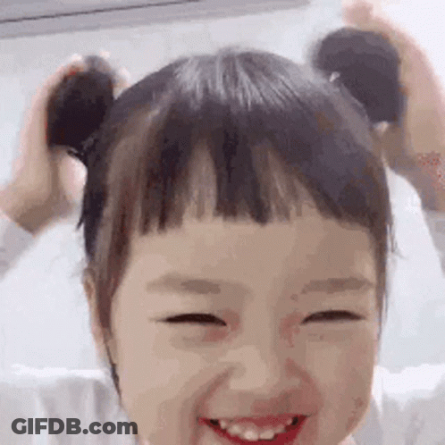 Little Girl With Pigtails Smiling Holding Hair GIF