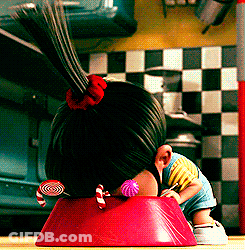 Little Girl With Ponytail Sitting In Red Bowl With Lollipop GIF