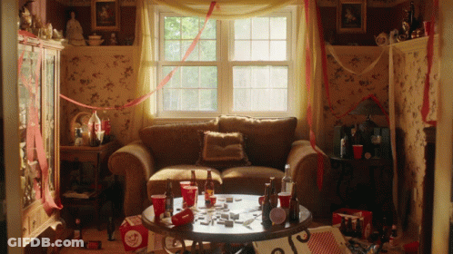 Living Room With Couch And Table Full Of Bottles And Cups GIF