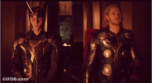 Loki And Thor Standing Next To Each Other In A Dark Room GIF