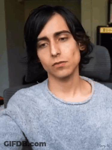 Long-Black-Haired Young Man Gray Sweater Looking At Camera GIF