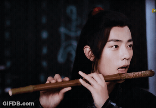 Long Hair Man Playing Flute Next To Sign A GIF