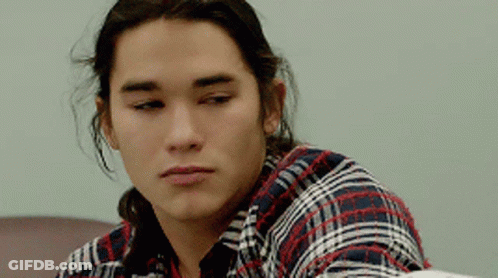 Long-Haired Young Man In Plaid Shirt Looking At Camera GIF