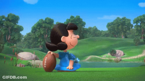 Lucy Brown Is Holding A Football While Charlie Brown Is Looking On GIF