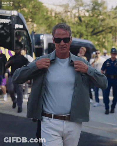 Man Adjusting Shirt In Front Of Bus Saying Wat Sports GIF