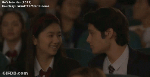 Man And Girl Looking At Each Other In Movie Theatre GIF