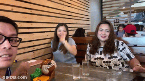 Man And Two Women At Table With Stuffed Monkey GIF