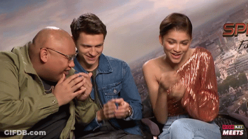 Man And Two Women Laughing In Front Of Pop Buzz Meets Sign GIF