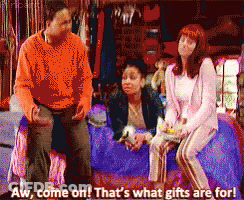 Man And Two Women Sitting On Bed Saying Aw Come On Thats What Gifts Are For GIF