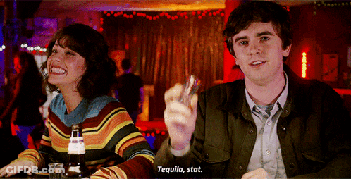 Man And Woman At Bar Holding Shot Glass Says Tequila Stat GIF