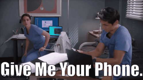 Man And Woman At Desk Saying Give Me Your Phone GIF