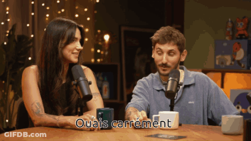 Man And Woman At Table With Microphones Ouais Carrément GIF