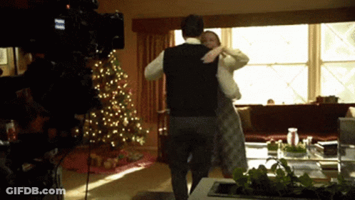 Man And Woman Dancing In Front Of Christmas Tree GIF