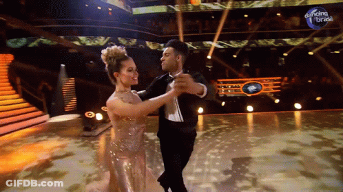 Man And Woman Dancing In Front Of Dancing Brasil Sign GIF