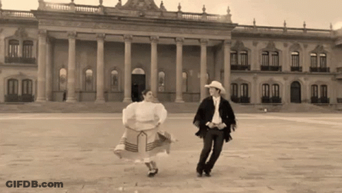 Man And Woman Dancing In Front Of Large Building GIF