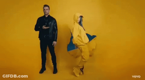 Man And Woman Dancing In Front Of Yellow Wall GIF