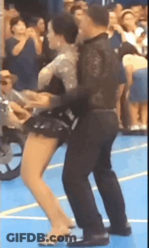 Man And Woman Dancing On Blue Floor With Crowd GIF