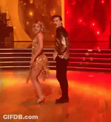 Man And Woman Dancing On Red-Lit Stage GIF