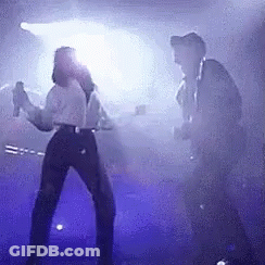 Man And Woman Dancing On Stage With Purple Lights GIF
