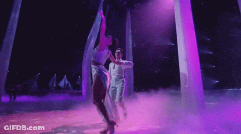 Man And Woman Dancing On Stage With Purple Lights GIF