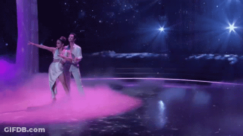 Man And Woman Dancing On Stage With Purple Smoke GIF