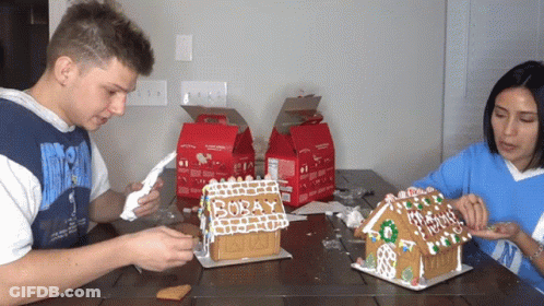 Man And Woman Decorating Gingerbread Houses GIF