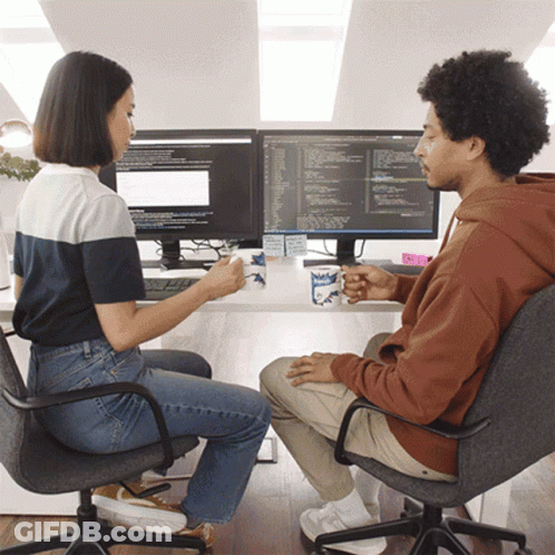 Man And Woman Drinking Coffee At Two Monitors Mugs Saying Milk GIF