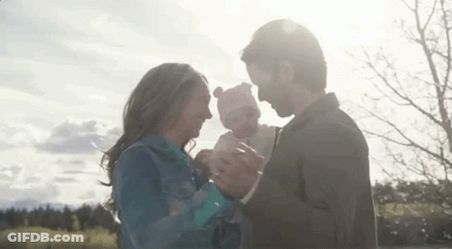 Man And Woman Holding Baby In Park GIF