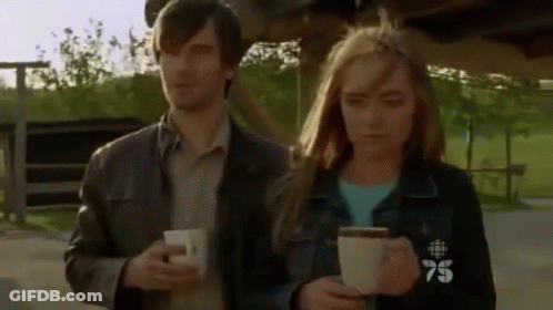 Man And Woman Holding Coffee With 75 On Jackets GIF