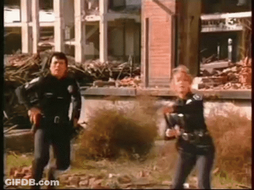 Man And Woman Holding Guns At Destroyed Building GIF