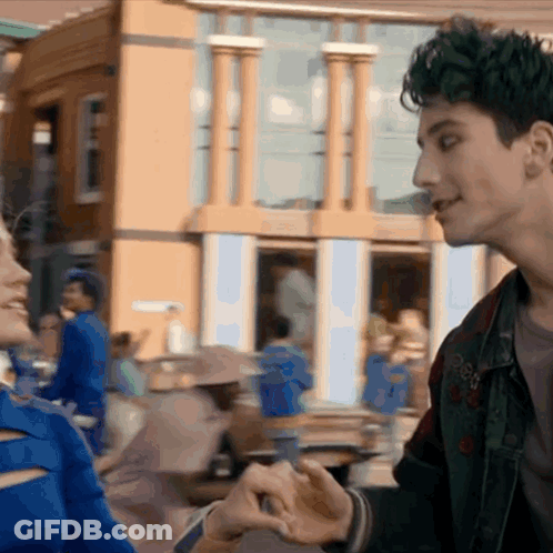 Man And Woman Holding Hands In Front Of Disney Building GIF