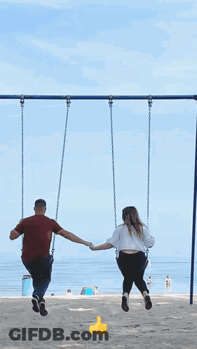 Man And Woman Holding Hands Swinging On Beach GIF