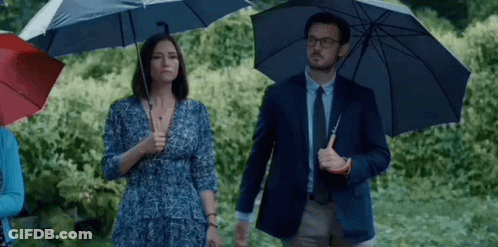 Man And Woman Holding Umbrellas In Rain GIF