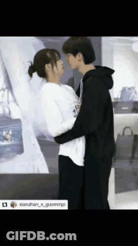 Man And Woman Hugging And Kissing In Front Of Purse Display GIF