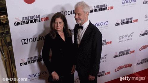 Man And Woman In Front Of American Cinematheque Wall GIF