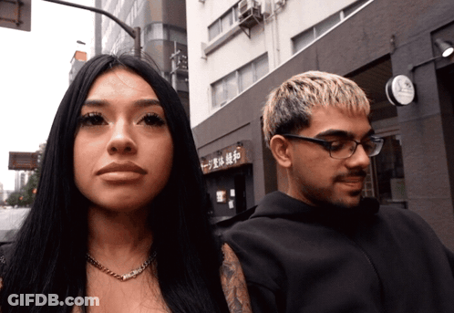 Man And Woman In Front Of Building With Chinese Characters GIF