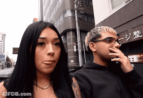 Man And Woman In Front Of Building With Chinese Writing GIF
