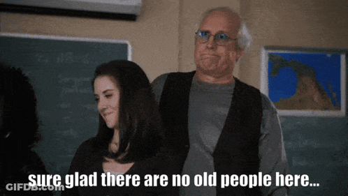 Man And Woman In Front Of Chalkboard Saying Sure Glad There Are No Old People Here GIF